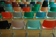 Verschiedenfarbige aufgereihte Stühle in einem Saal