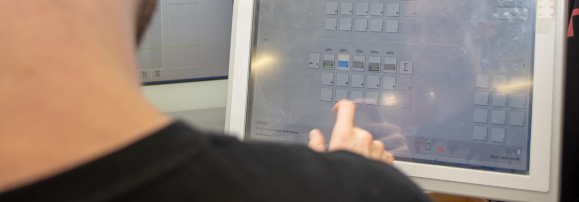 Ein Mann dr&uuml;ckt auf einen Touchscreen in einer Fabrik