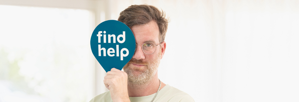 Mann h&auml;lt Tafel mit Aufschrift "Find help" vor sein Gesicht