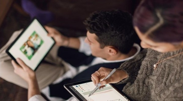 Bild zu Diplom anerkennen, Frau mit Tablet in der Hand, im Hintergrund ein Mann mit einem Tablet